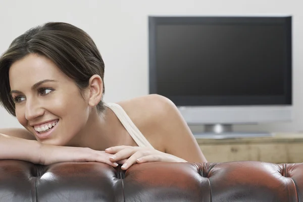 Jovem mulher no sofá sorrindo — Fotografia de Stock