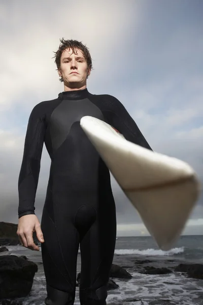 Uomo che tiene tavola da surf sulla spiaggia — Foto Stock