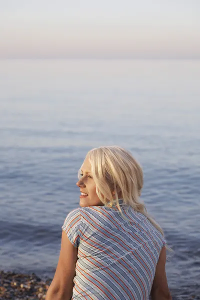 Femme assise sur la plage — Photo