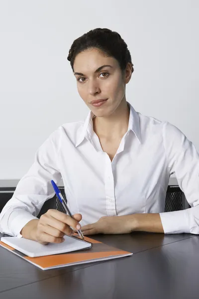 Zakenvrouw schrijven aan balie — Stockfoto