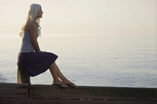 Woman sitting on wooden bale — Stock Photo, Image