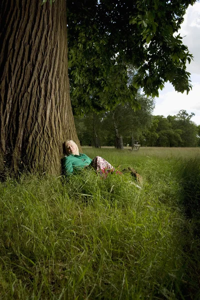 Vrouw zitten onder een boom — Stockfoto