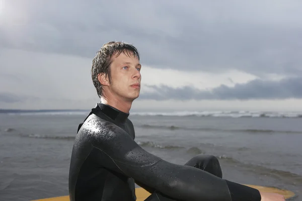 Surfer sitting on surfboard — Stock Photo, Image