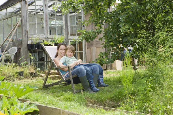 Matka siedzi z synem w ogrodzie — Zdjęcie stockowe