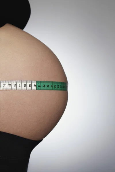 Těhotná žena s páskou opatření — Stock fotografie