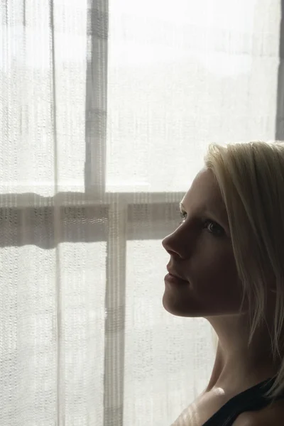 Kvinna som står vid fönstret — Stockfoto