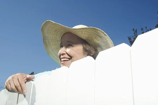 Mujer mirando por encima de la cerca del jardín — Foto de Stock