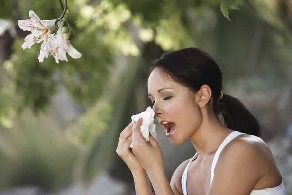 Vrouw niezen onder boom — Stockfoto