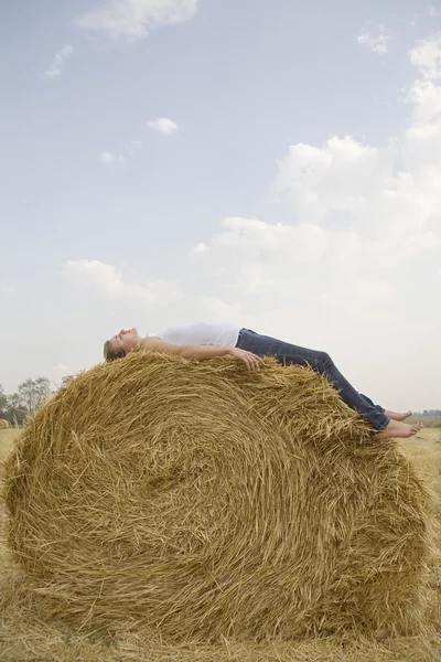Woman resting on hay bale — Stock Photo, Image