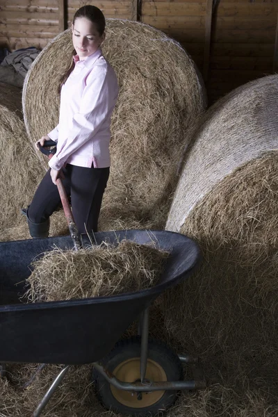 Girl shoveling hay — Stock Photo, Image