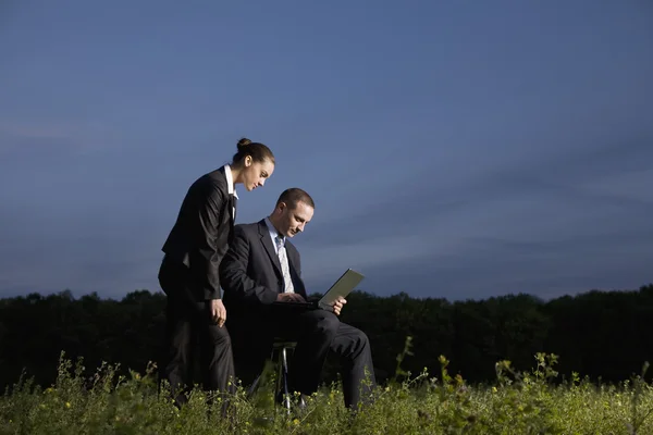 Couple using laptop in field — Stock Photo, Image
