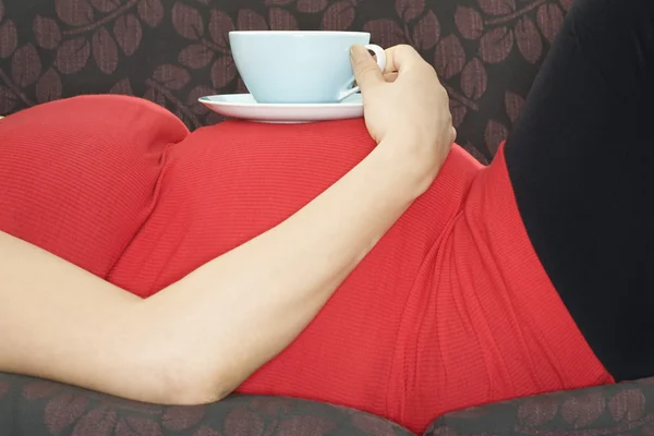Donna incinta con bevanda sul divano — Foto Stock