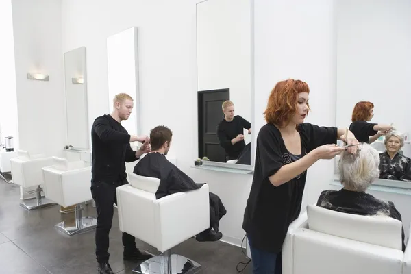 Styliści wyciąć włosy klientów w salonie unisex — Zdjęcie stockowe
