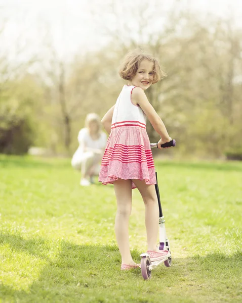 女孩骑滑板车穿过公园 — 图库照片