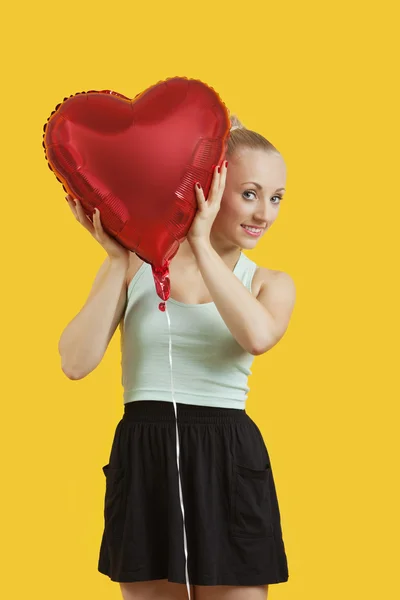 Kobieta zaglądając przez balon w kształcie serca — Zdjęcie stockowe