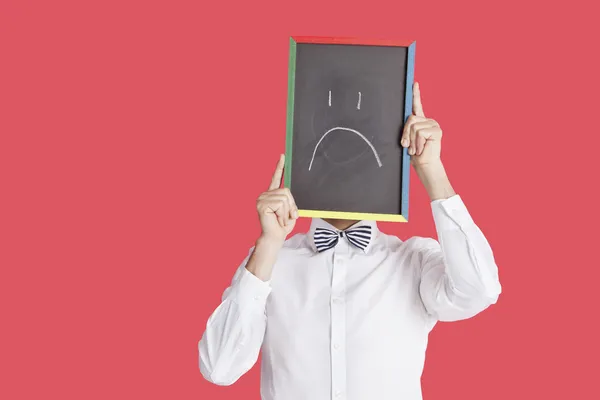 Homem segurando triste sinal de rosto sorridente — Fotografia de Stock