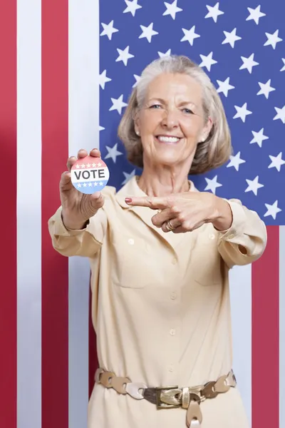 Senior woman pointing at election badge — Stock Photo, Image