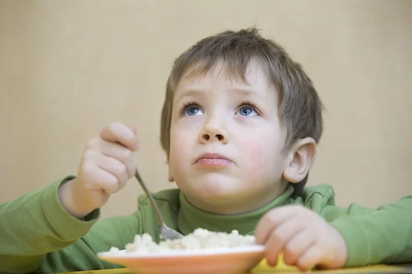 Niño mirando hacia arriba mientras come — Foto de Stock