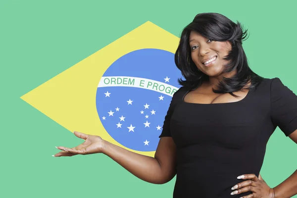 Woman holding out empty palm over Brazilian flag — Stock Photo, Image