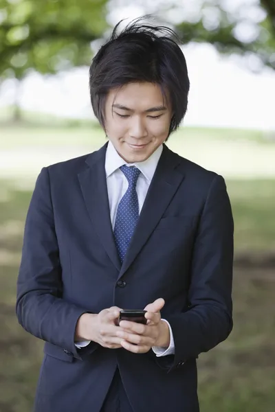 Бизнесмен, использующий мобильный телефон в парке — стоковое фото