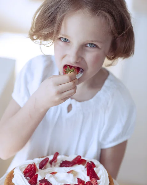 Girl with cake eating strawberry — Stock Photo, Image