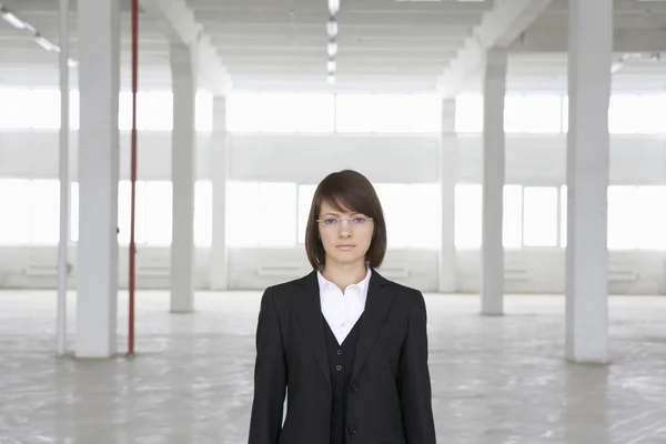 Business woman stands in empty warehouse — Stock Photo, Image