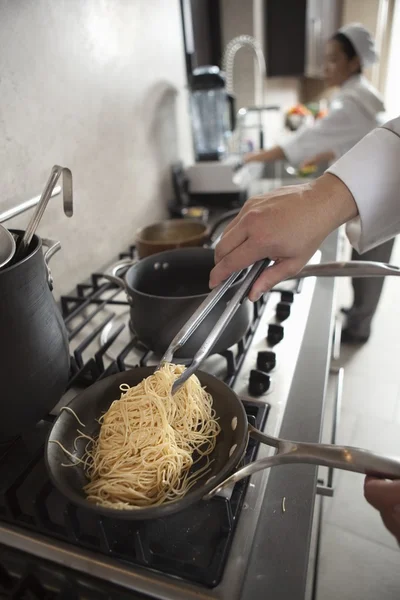 Chef heating spaghetti on hob — Stock Photo, Image