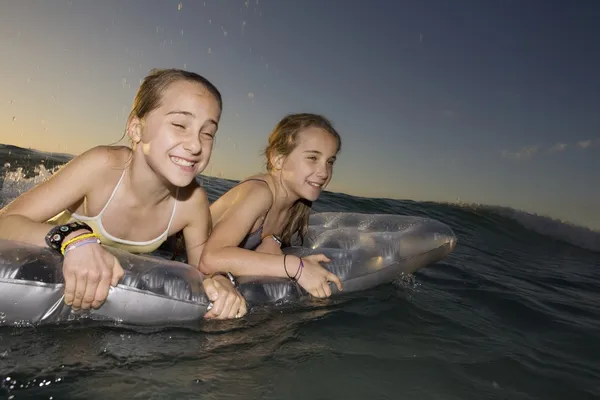 Zwillingsschwestern winken Surfen auf Luftmatratze — Stockfoto