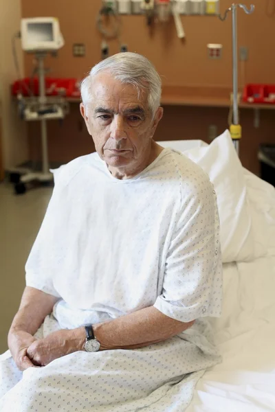 Elderly man sitting on hospital bed — Stock Photo, Image