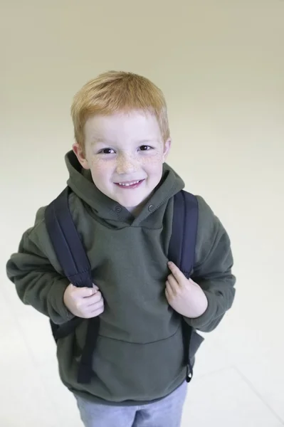 Skolpojke med redhair och fräknar står med ryggsäck — Stockfoto