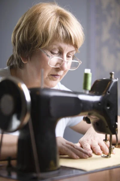 Mujer madura trabaja en la máquina de coser — Foto de Stock