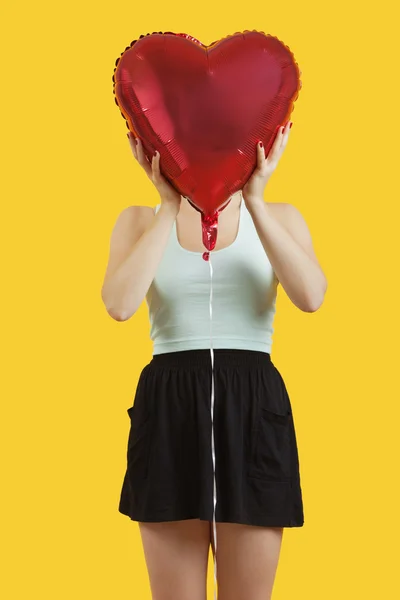 Vrouw verstopt achter hartvormige ballon — Stockfoto