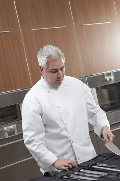 Mid- adult chef chooses knife — Stock Photo, Image