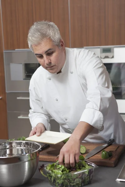 Mid- adult chef prepares salad — Stock Photo, Image