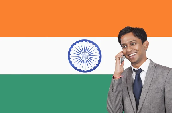 Бизнесмен, использующий телефон над индийским флагом — стоковое фото