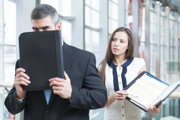 Empresario se esconde de compañero de trabajo detrás de la carpeta — Foto de Stock