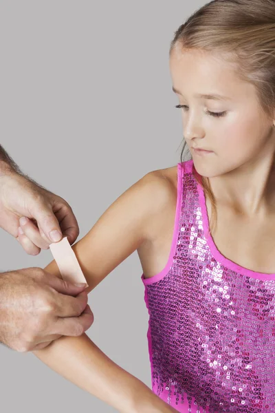 Appliquer un bandage adhésif sur le bras de la fille — Photo