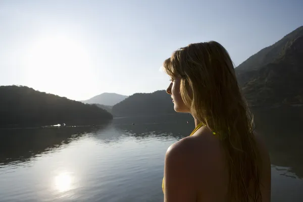 Wanita pirang melihat keluar di pagi hari matahari terbit di atas danau — Stok Foto