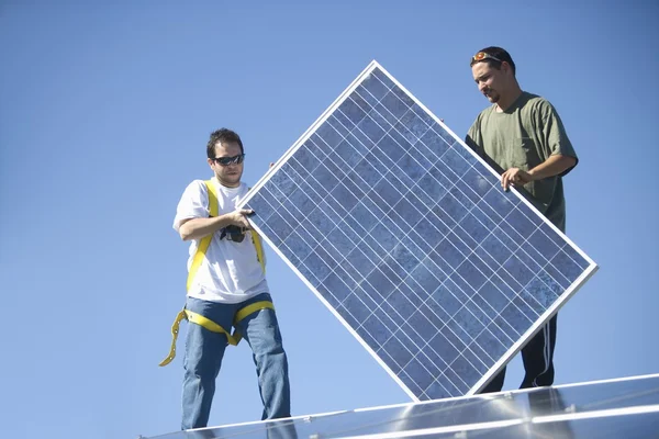 Homens levantando um painel solar — Fotografia de Stock