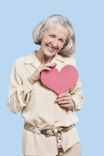 Starší žena drží červené papírové srdce — Stock fotografie