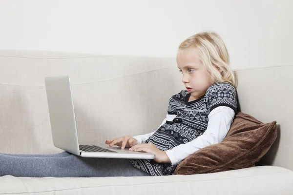 Chica usando el ordenador portátil en el sofá — Foto de Stock