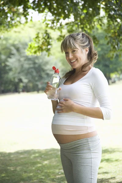 Pregnant woman in park drinking water — Stock Photo, Image