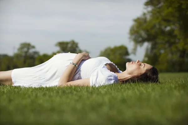 Hamile kadın çim üzerinde yalan — Stok fotoğraf