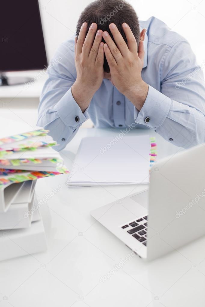 businessman with head in hands at his desk