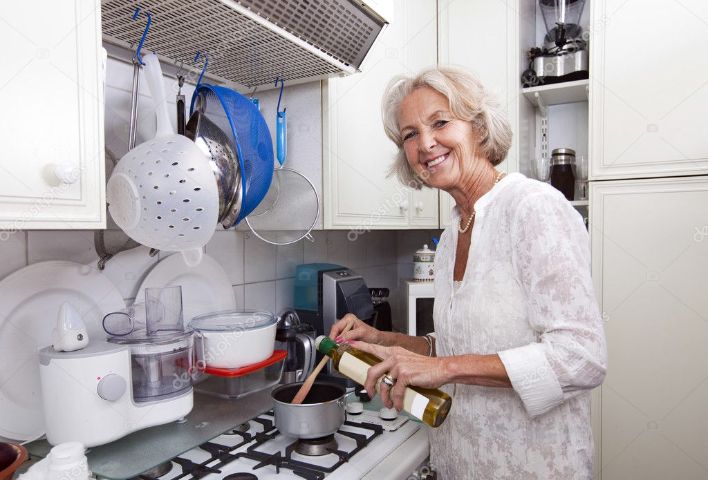 Senior woman adding olive oil to saucepan