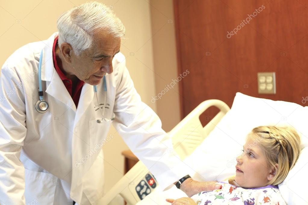 Elderly doctor leans over patient in pediatrics ward
