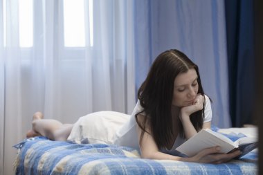 kadın yatakta yatarken ve kitap okuma