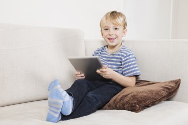 tablet pc kanepe üzerinde tutan çocuk