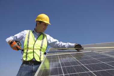 Maintenance worker measures solar cells clipart