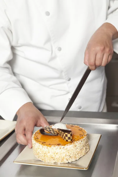 Chef fatiar bolo na cozinha — Fotografia de Stock